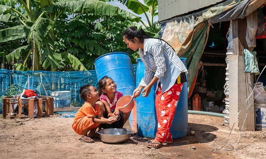 A World Vision staff is helping the two children wash their hands. (Cambodia, 2023)