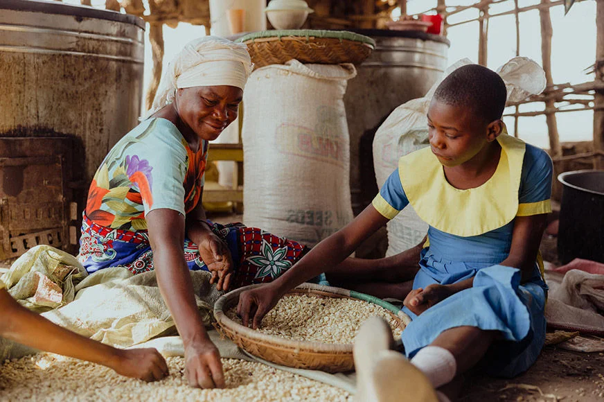 A teacher and a student are preparing lunch for a World Vision school feeding program. (Kenya, 2023)