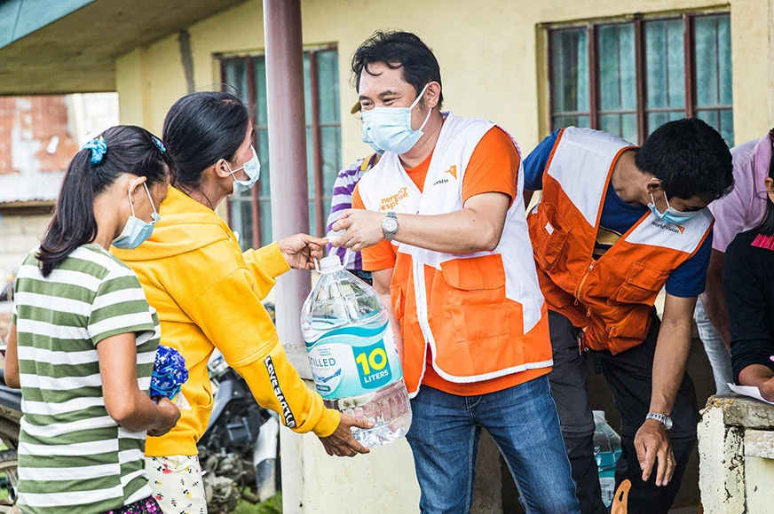 A World Vision staff is handing 10 liters of bottled water to two women during a food aid relief in Bohol, Philippines. (Philippines, 2022)