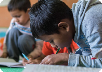 Child writing on desk at school.