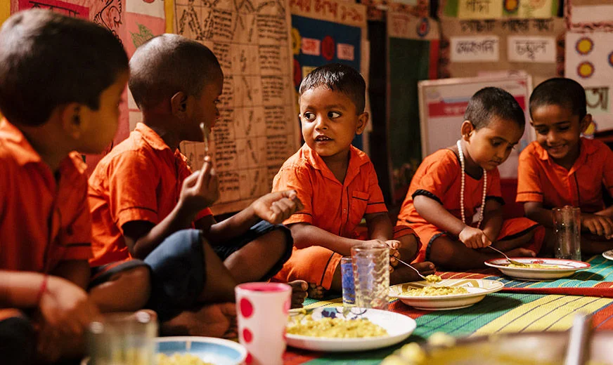Five children in school uniform are eating food together. (Bangladesh, 2023)