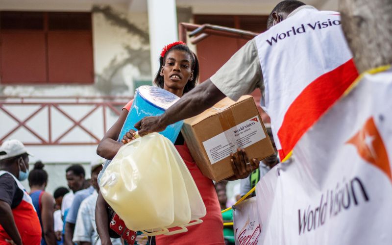 A woman gathers emergency water bottles from a World Vision staff